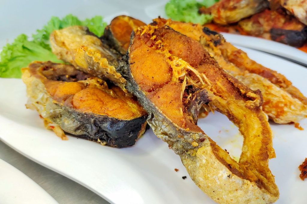 Ikan patin goreng krispi dengan lapisan tepung keemasan, tekstur renyah di luar dan daging lembut di dalam, disajikan dengan sambal dan irisan jeruk nipis.