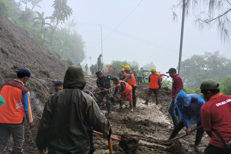 Petugas dan warga membersihkan material longsor di jalur Malang–Bromo