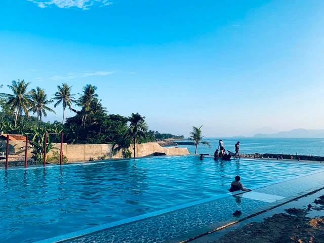 Panorama Pantai Canti di Lampung Selatan dengan hamparan pasir, kolam renang, dan pemandangan sunset berlatar Gunung Rajabasa.