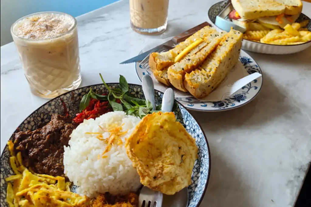 Nasi langgi khas Cirebon dengan lauk lengkap seperti serundeng, telur dadar, orek tempe, sambal goreng, dan kerupuk di warung legendaris Cirebon.