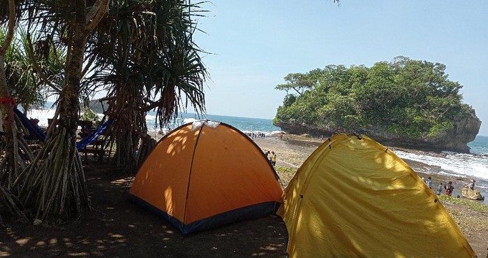 Area camping di Pantai Madasari Pangandaran dengan pemandangan Samudra Hindia saat matahari terbenam.